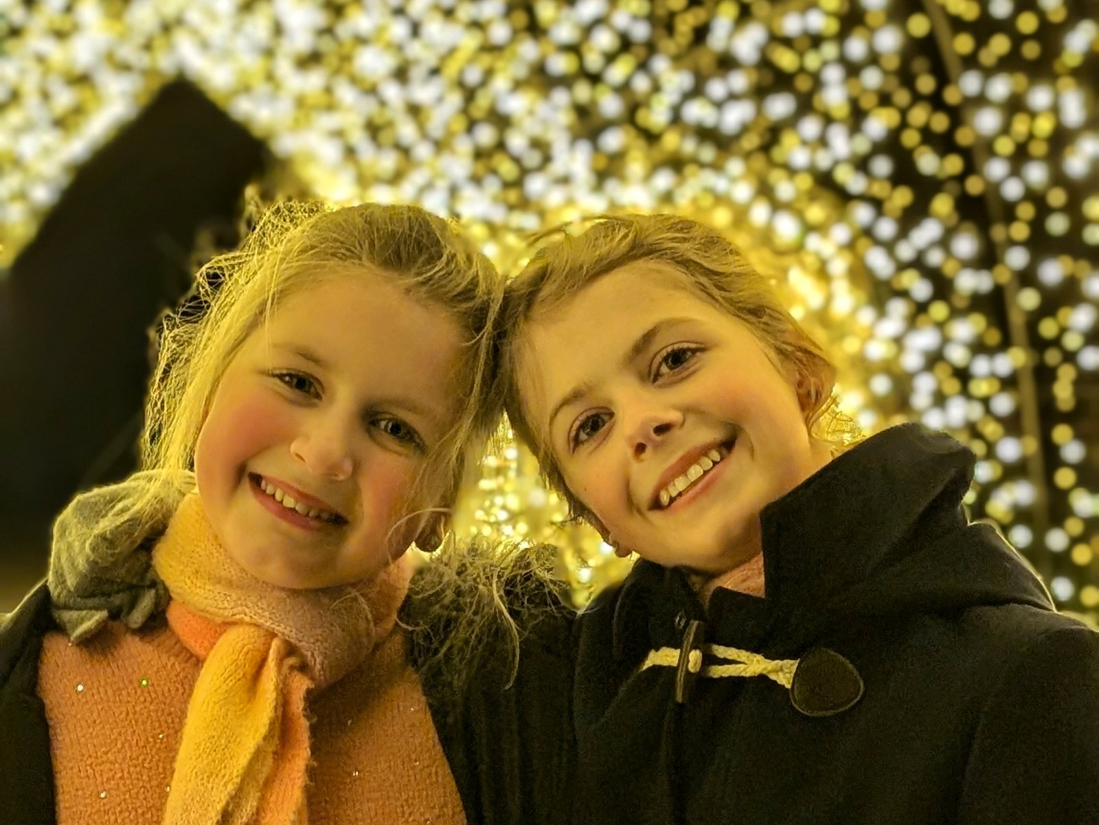 Pocket Money Performers Libby and Lia standing in front of a light display
