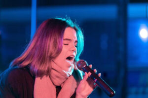 Hannah Bowen singing on stage wearing a scarf