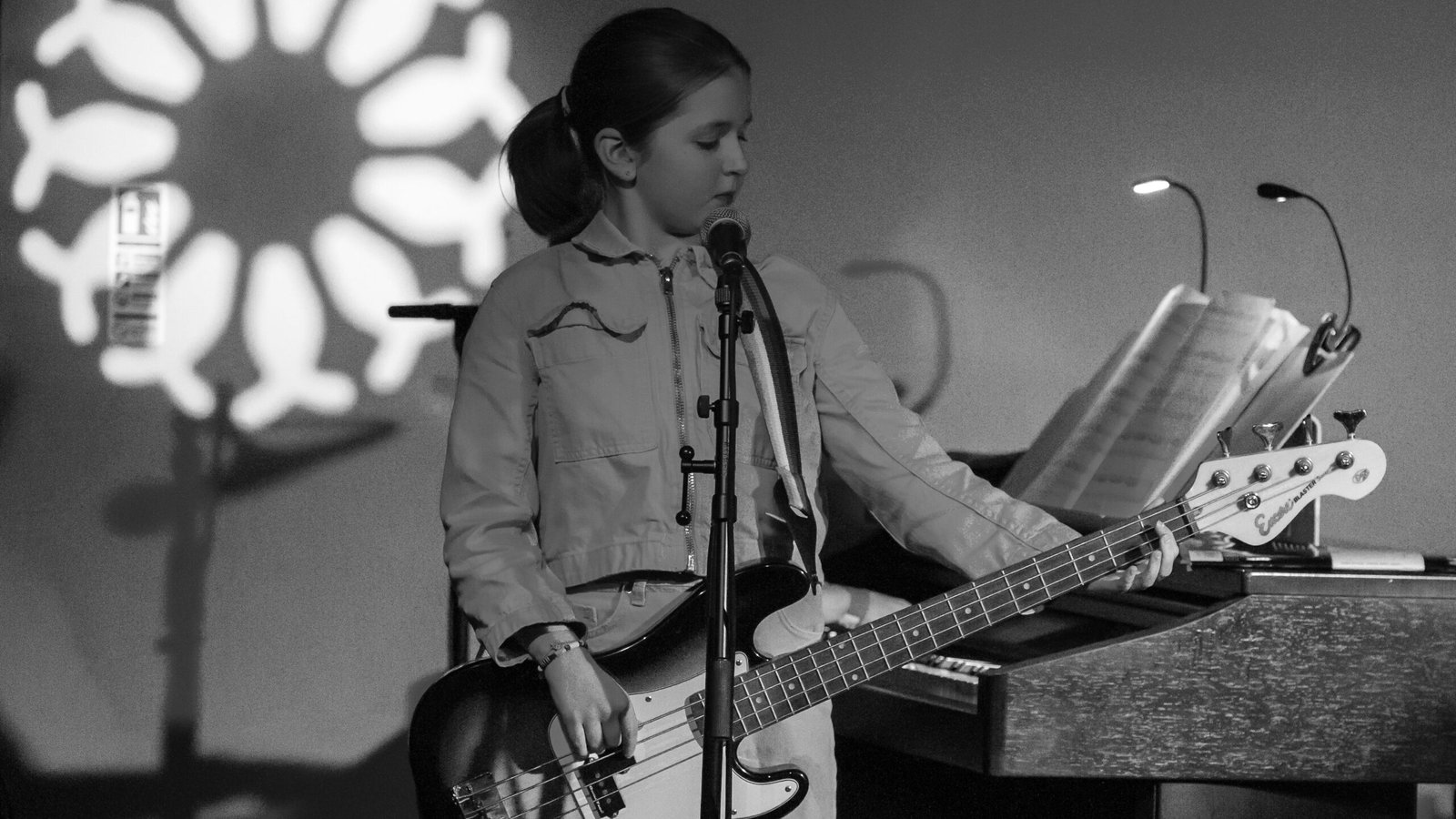 Pocket money performer Evelia Ray singing and playing bass guitar